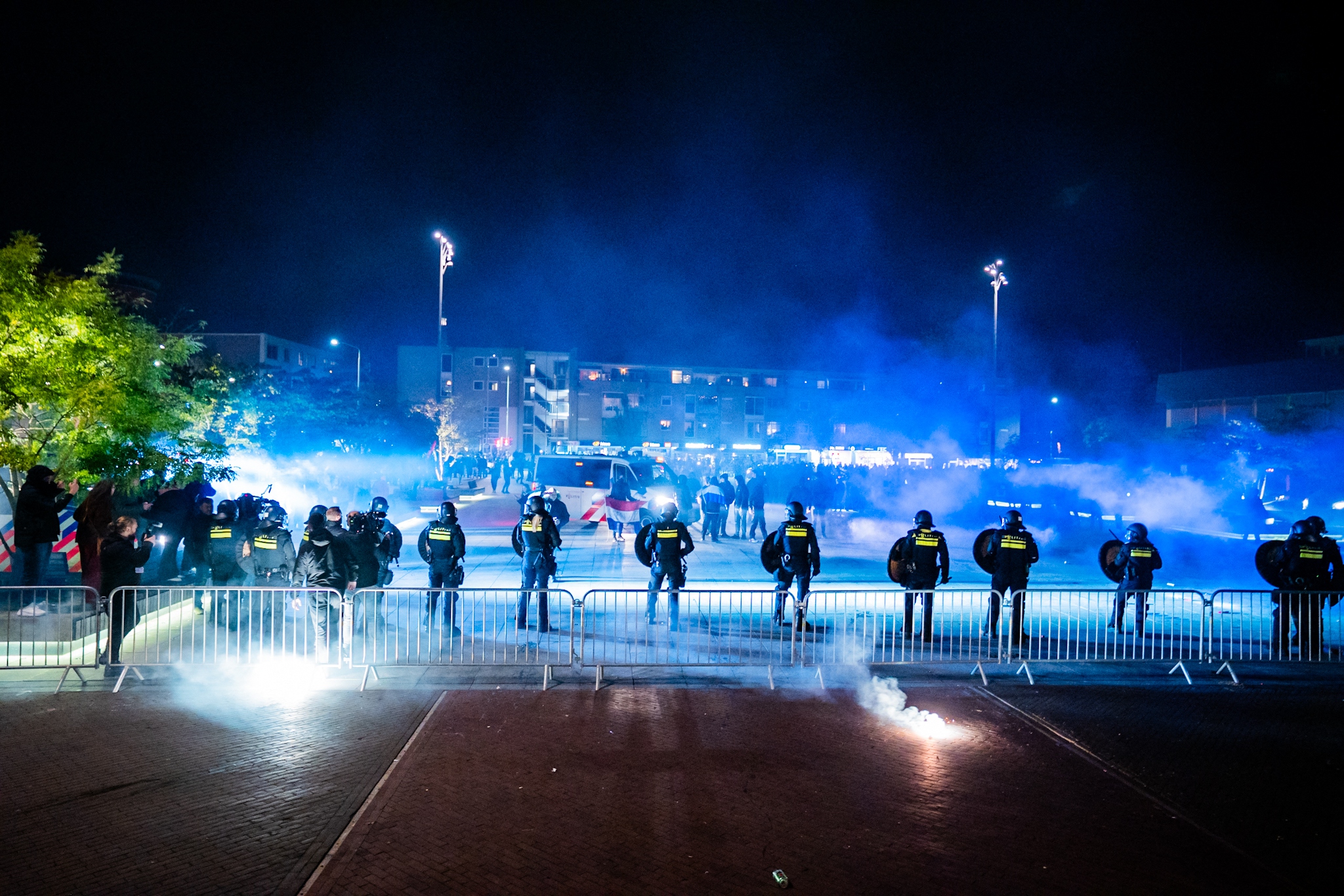 Police officers in riot gear facing a crowd during a demonstration against an asylum seekers' center.