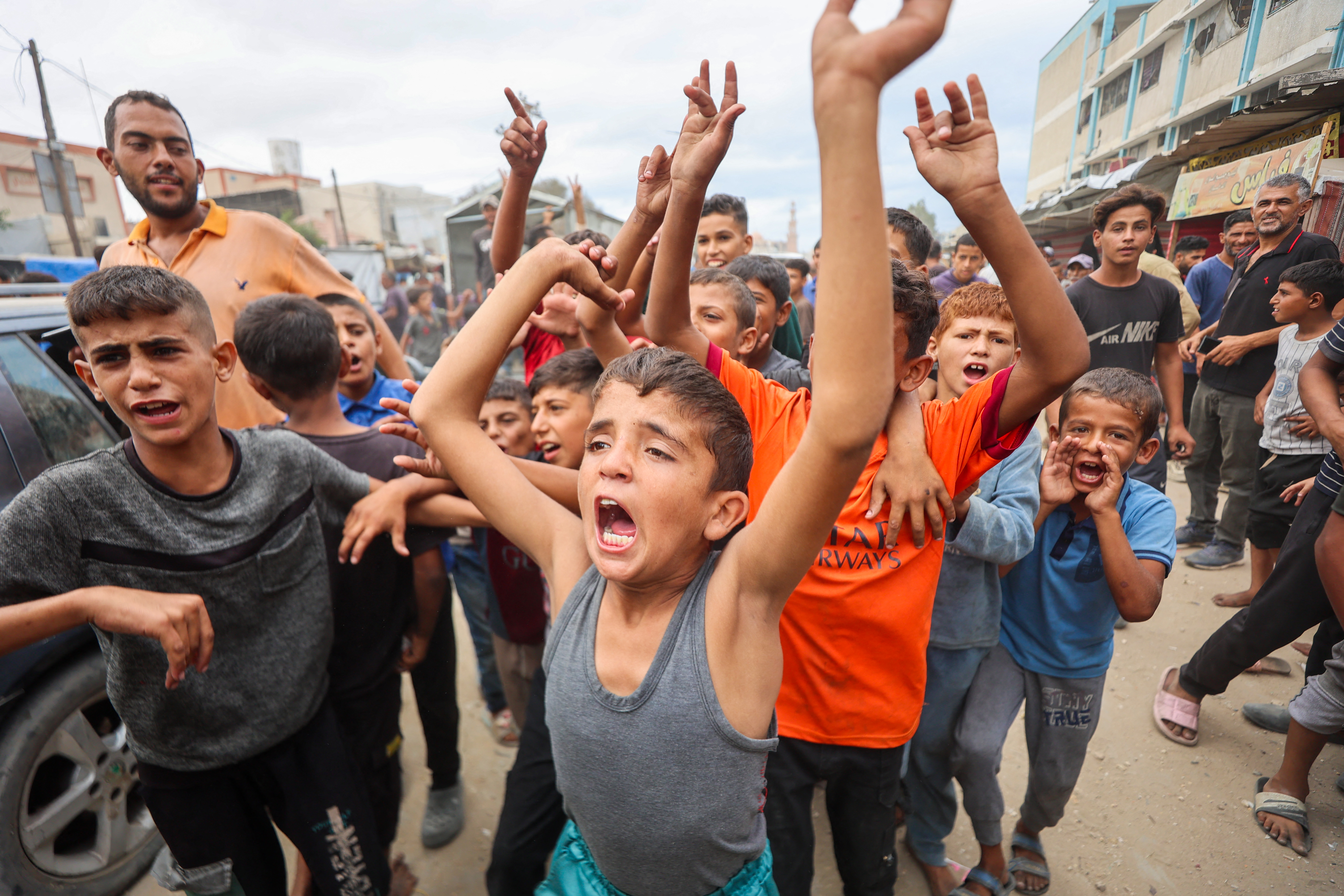 Palestinian children in Khan Yunis celebrate the Gaza ceasefire deal with raised arms and open mouths.