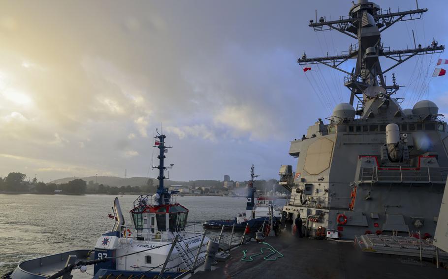 The deck of a Navy destroyer on a partly cloudy day at sea, with sunlight emerging through in the top right corner.
