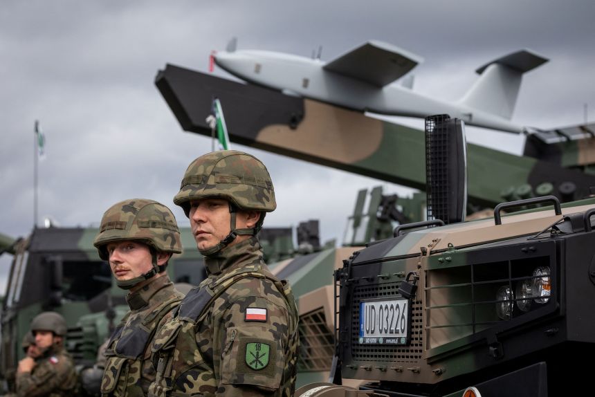 Polish soldiers stand next to a Polish 