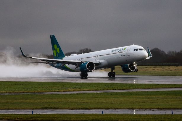 An Aer Lingus flight kicks up spray as it lands at Manchester Airport