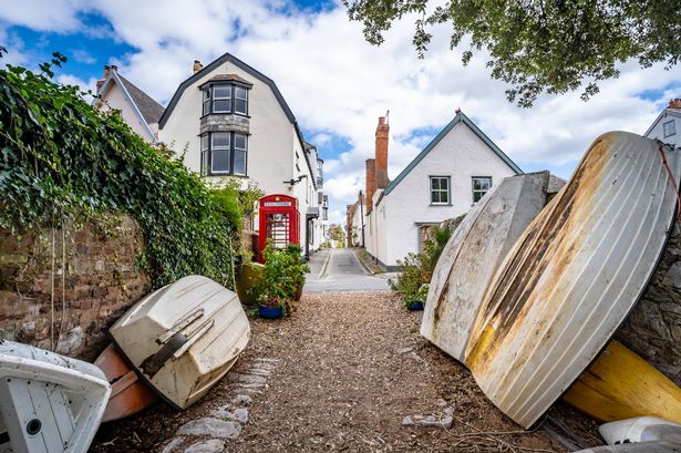 Row boats stacked by an on old telephone box in Topsham, Devon