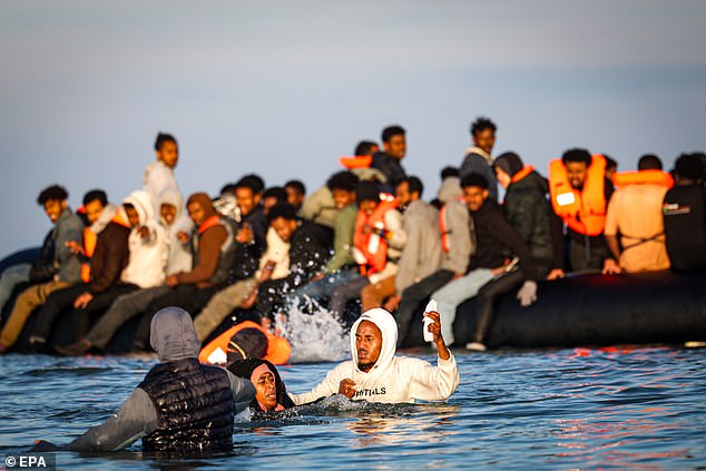 Migrants board an inflatable boat in Gravelines, northern France, as they prepare to cross the English Channel