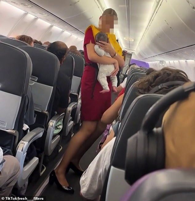 A Virgin Australia flight attendant (pictured) helped a mother by holding her baby while she settled her other children