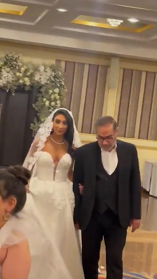 The bride wore a strapless white dress with a low neckline and entered the grand room to cheers and music