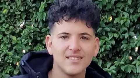 West Yorkshire Police Ahmad Mamdouh Al Ibrahim looks at the camera. He has curly black hair and is wearing a black hooded coat