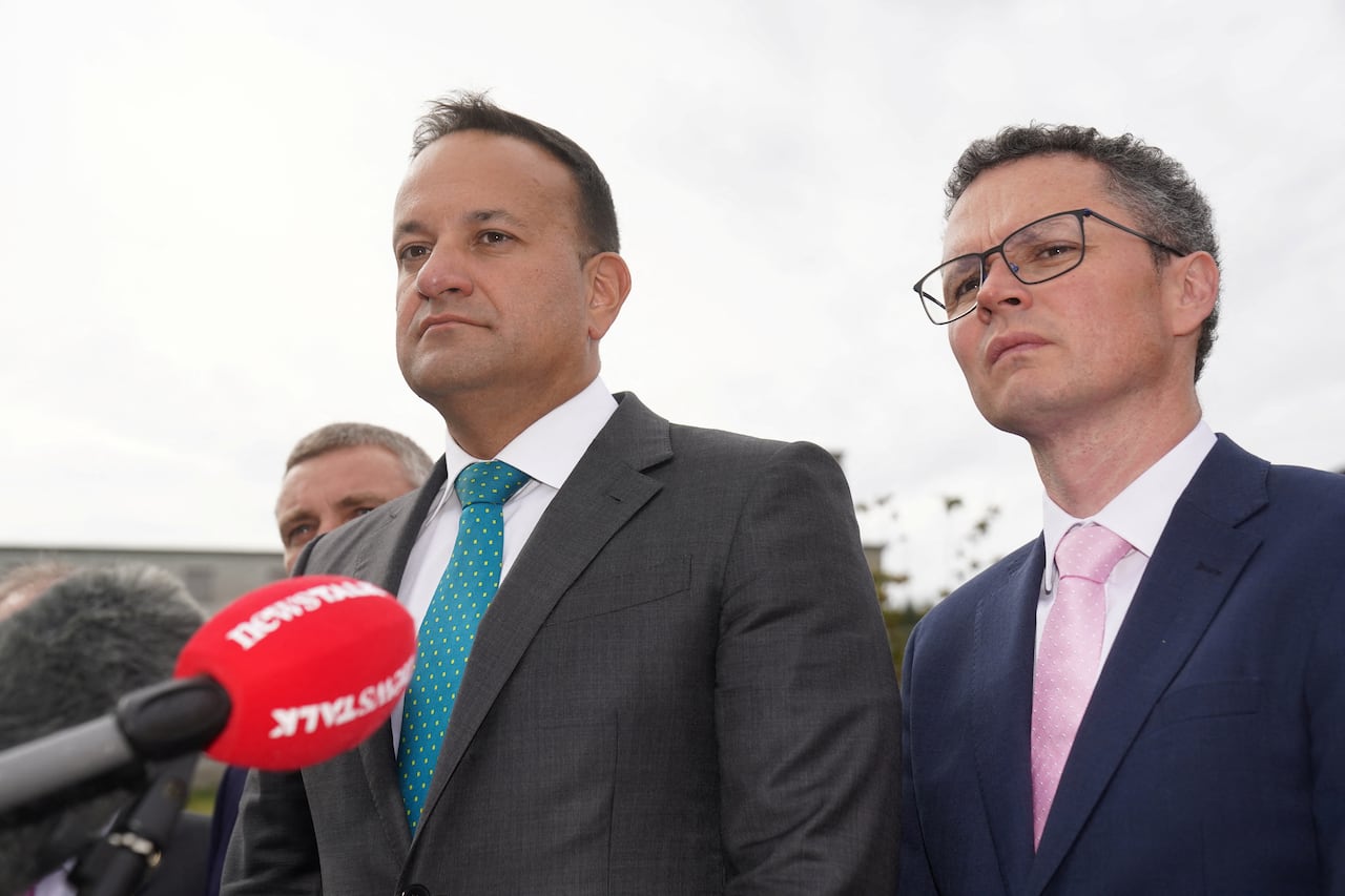 Two men in suits stand at a microphone