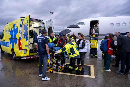 Des enfants palestiniens blessés et leurs proches sont escortés par du personnel médical jusqu’à une ambulance, à la suite de leur évacuation de la bande de Gaza, à l’aéroport de Zurich, en Suisse, le 24 octobre 2025.