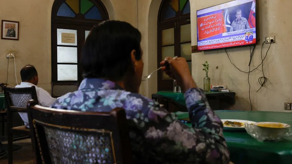 People watch a televised press briefing by Ahmed Sharif Chaudhry, Director General of the Inter-Services Public Relations wing of the Pakistan Armed Forces, in Karachi, Pakistan on October 10, 2025. - Akhtar Soomro/Reuters
