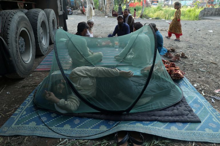 An Afghan man rests in a mosquito net tent beside a loaded truck as he prepares to return home, after Pakistan started to deport documented Afghan refugees, outside the United Nations High Commissioner for Refugees (UNHCR) repatriation centre in Nowshera, Pakistan August 27,2025. REUTERS/Fayaz Aziz