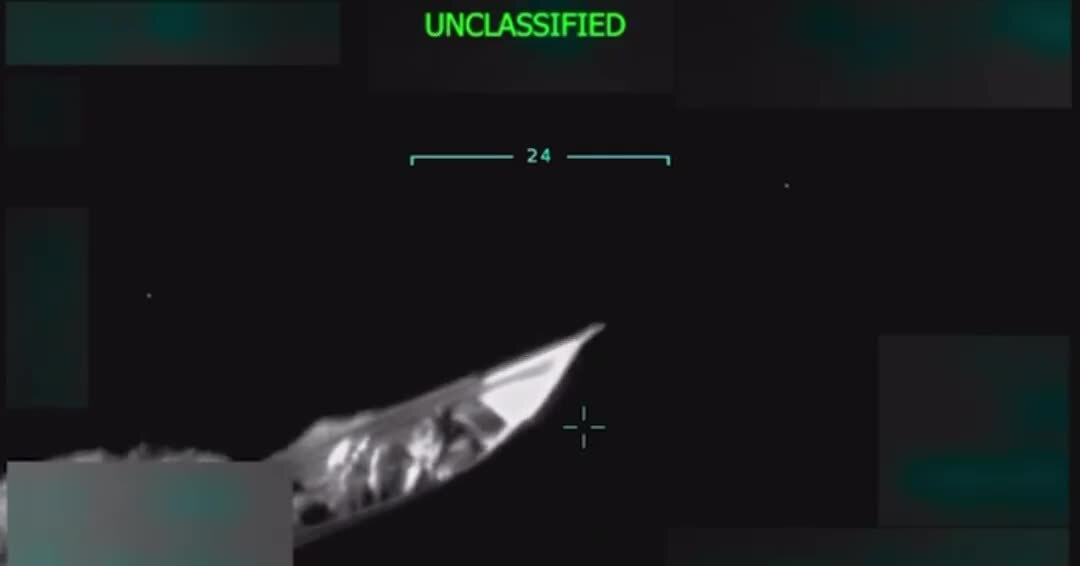 Still image of a boat from a video showing the boat being hit by a US attack, killing 11 people. A grainy black and white image with the word 