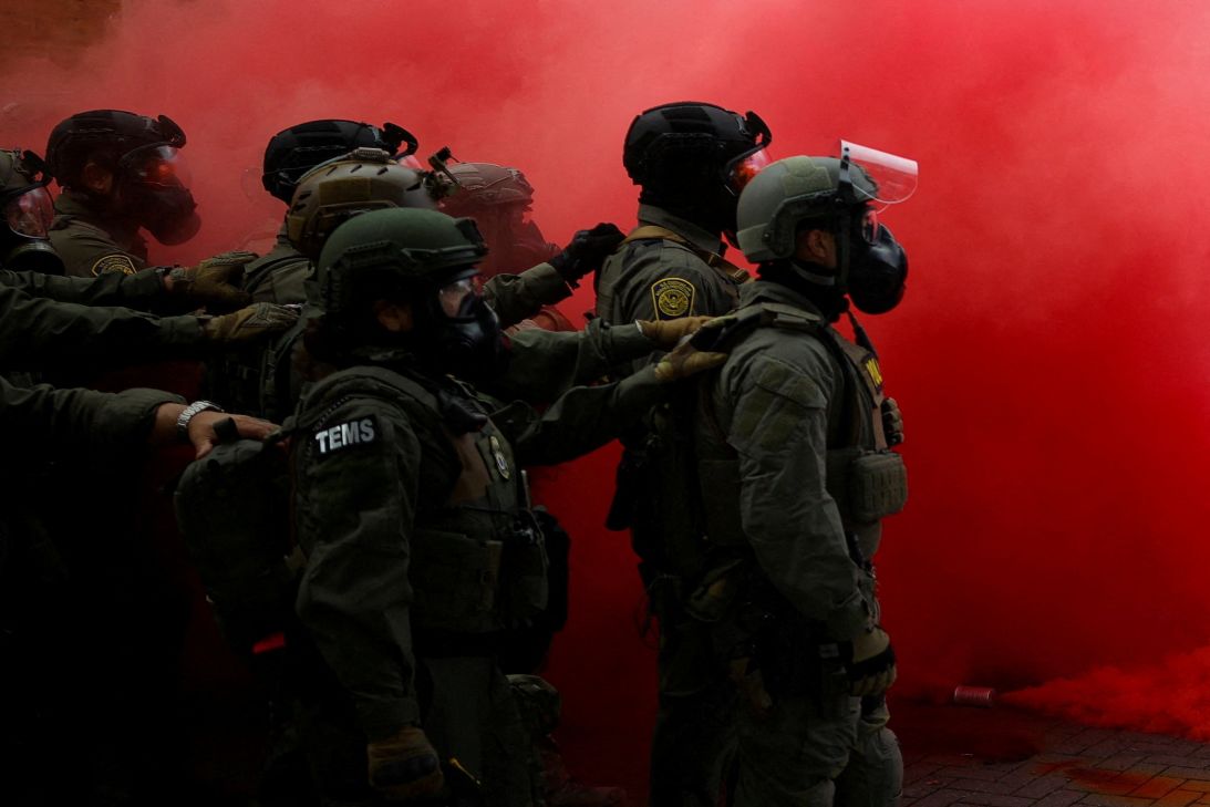 Law enforcement officers stand in smoke after a smoke grenade was released to disperse demonstrators in front of ICE headquarters in Portland, Oregon, on October 4.