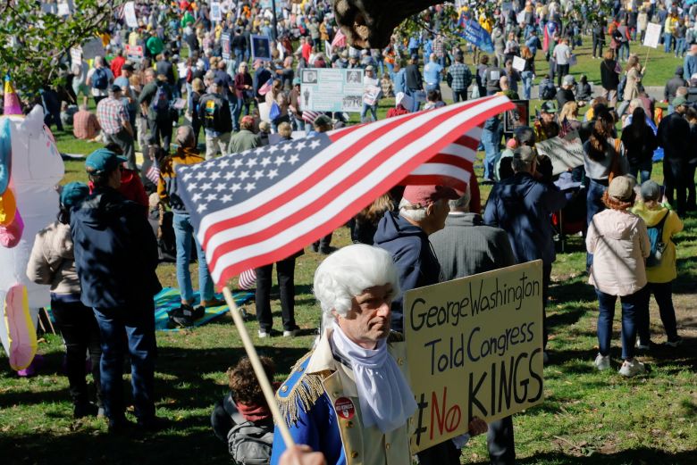 A person dressed as former US President George Washington displays a sign during a 