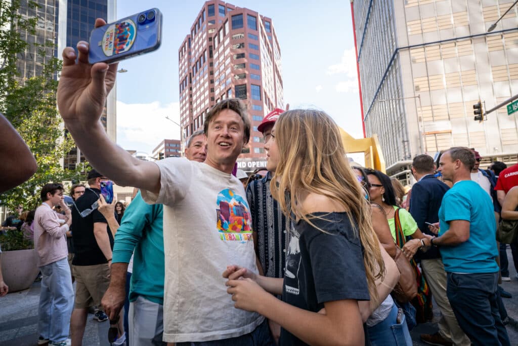 Denver Mayor Mike Johnston, center, snaps a selfie