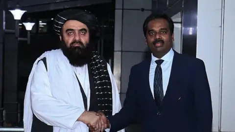 Randhir Jaiswal/MEA Twitter Amir Khan Muttaqi shakes hands with an Indian diplomat