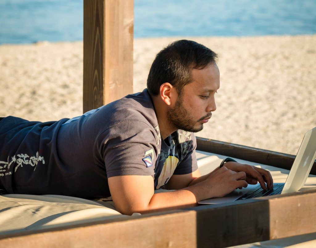 Photo: Digital nomad using laptop outdoors at a beach. Credit: Barbara Cameron Pix / Alamy