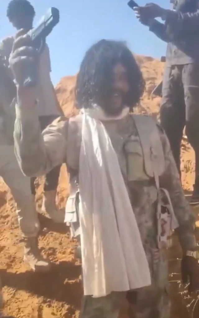 Abu Lulu holding a pistol in the air