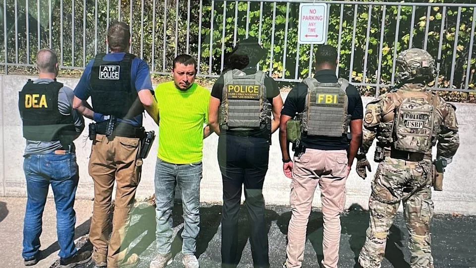 Police pose with Juan Espinoza-Martinez, whom officials allege is a Latin Kings gang member who called for the killing of Gregory Bovino, a top Border Patrol official (Department of Homeland Security)