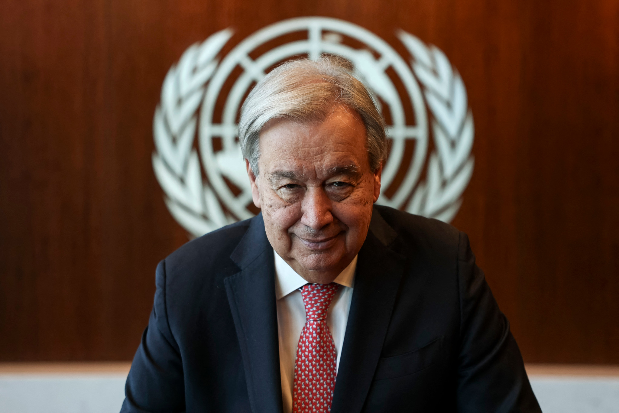 Le Secrétaire général de l’ONU, Antonio Guterres, pose pour un portrait avec le logo de l’ONU en arrière-plan avant la 80e session de l’Assemblée générale des Nations Unies à New York.