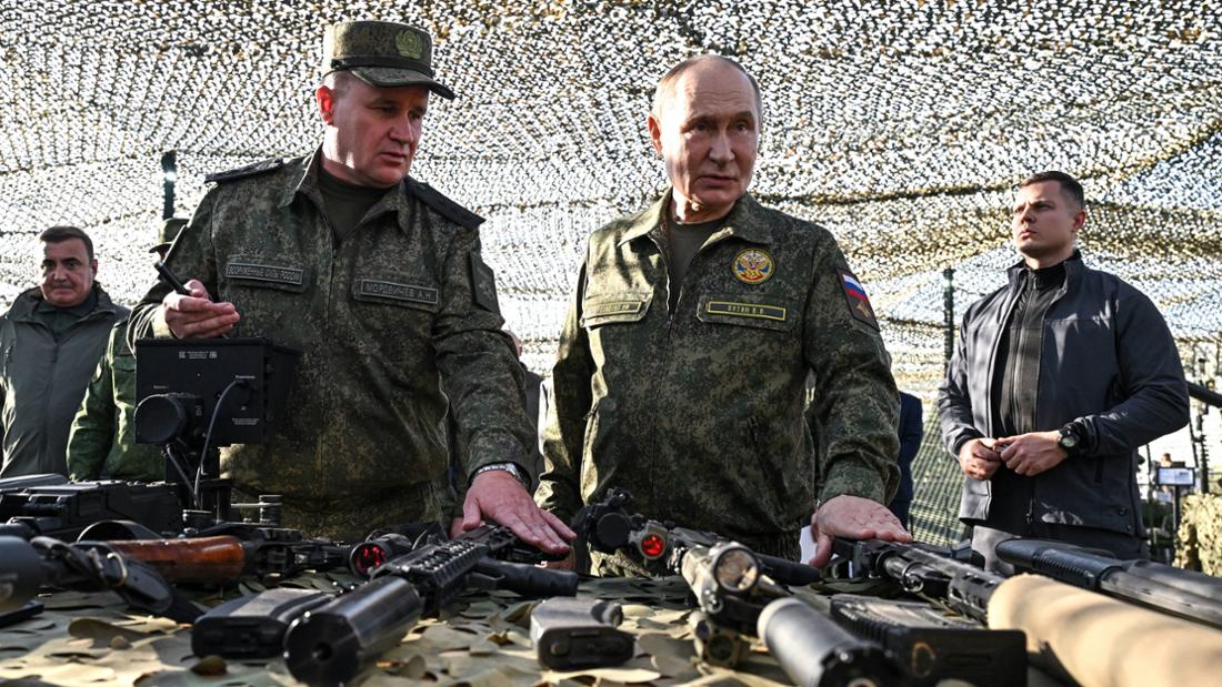 Wladimir Putin steht an eine Tisch mit Waffen