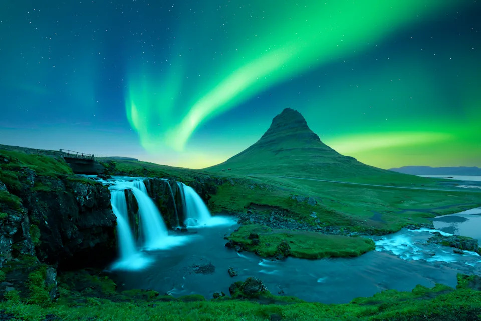 Incredible icelandic landscape with incredible sky with Northern lights over Kirkjufellsfoss waterfall. Kirkjufell volkano mountain and Polar lights in Iceland. Aurora borealis