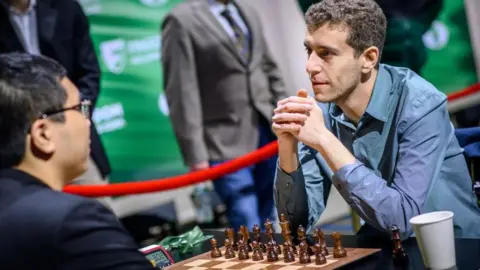International Chess Federation Naroditsky playing chess with spectators behind