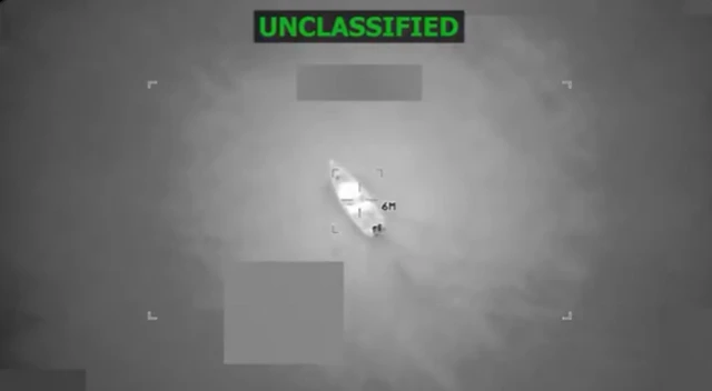 Imagen de cámara de vigilancia de un barco en el agua. Arriba se lee "desclasificado" en letras verdes.