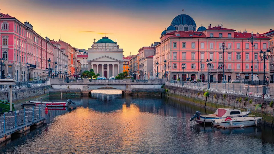 Colorful summer sunrise in Trieste, Italy, Europe. Great morning view of Canal Grande di Trieste and Church of Sant'Antonio Nuovo on background. Traveling concept background.