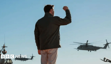JD Vance claps while at podium with dozens of marines standing behind him
