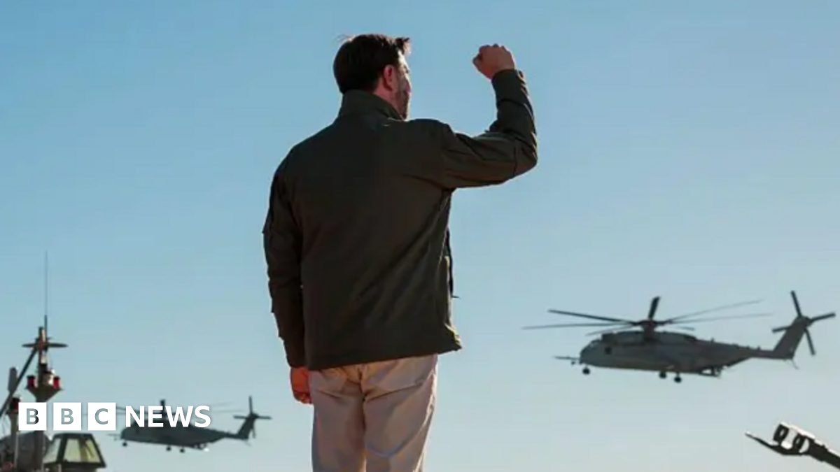 JD Vance claps while at podium with dozens of marines standing behind him