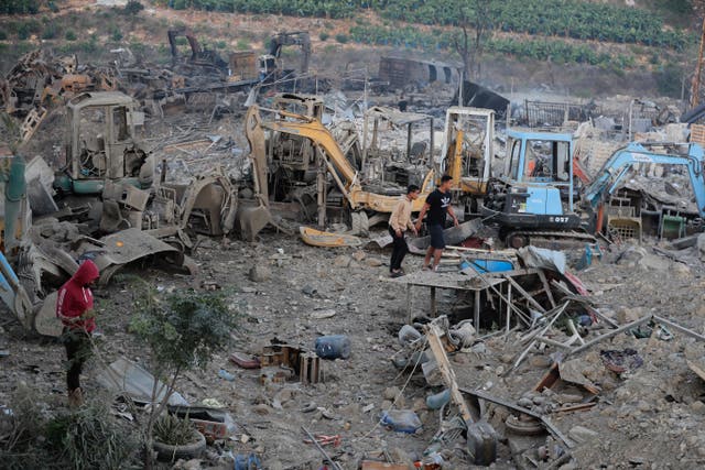 People gather at a site that sold heavy machinery, where a large number of vehicles were destroyed in Israeli air strikes, in the southern village of Msayleh, Lebanon