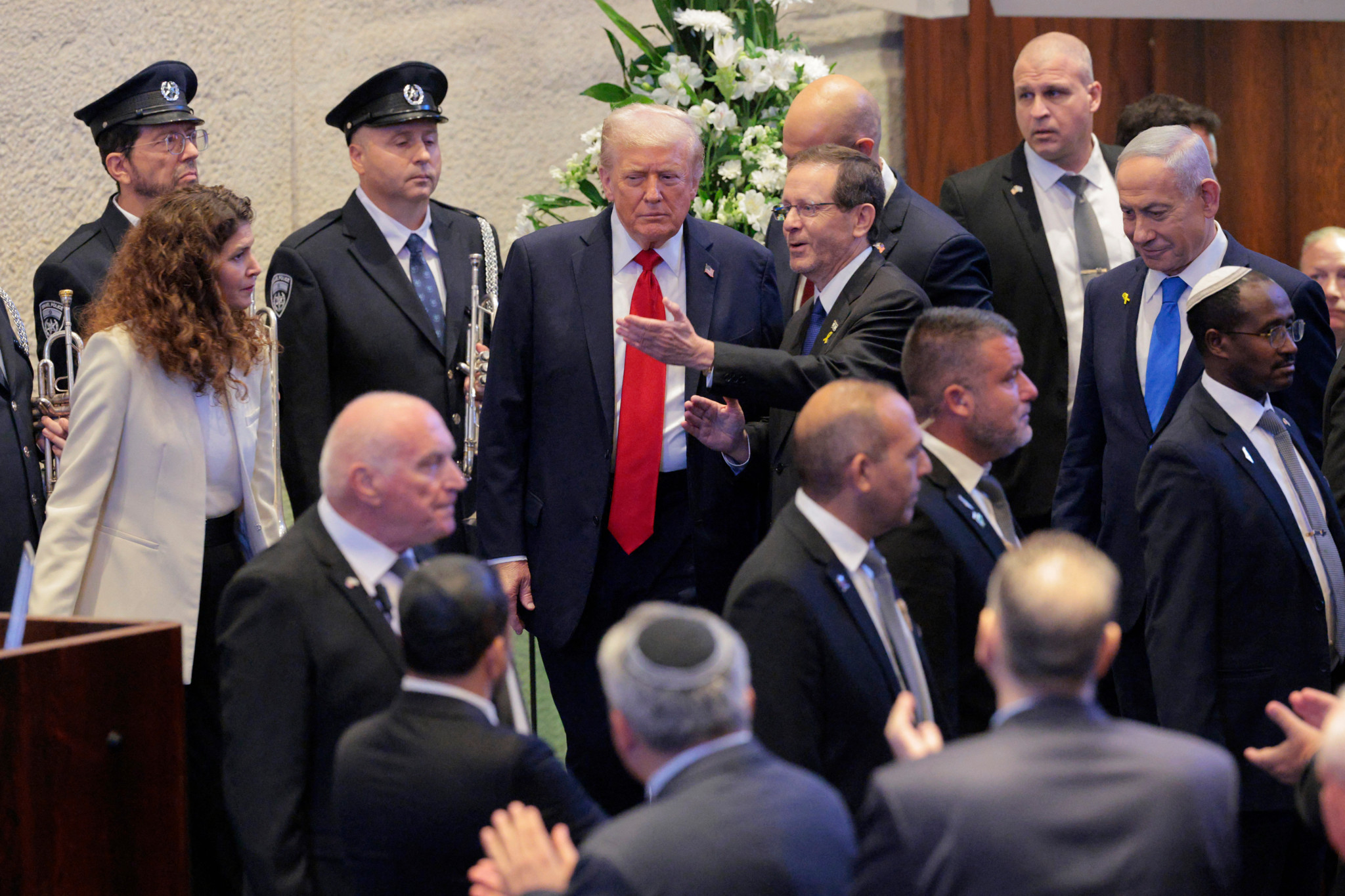 Le président américain Donald Trump au centre, arrive pour prononcer un discours au parlement israélien, la Knesset, à Jérusalem, entouré de plusieurs officiels et membres de la sécurité.