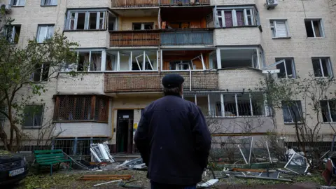 Reuters A man looks at a destroyed building in Kyiv