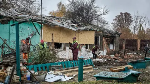 EPA Ukrainian workers work at the site of an airstrike on a private building in Kharkiv, northeastern Ukraine, 21 October.