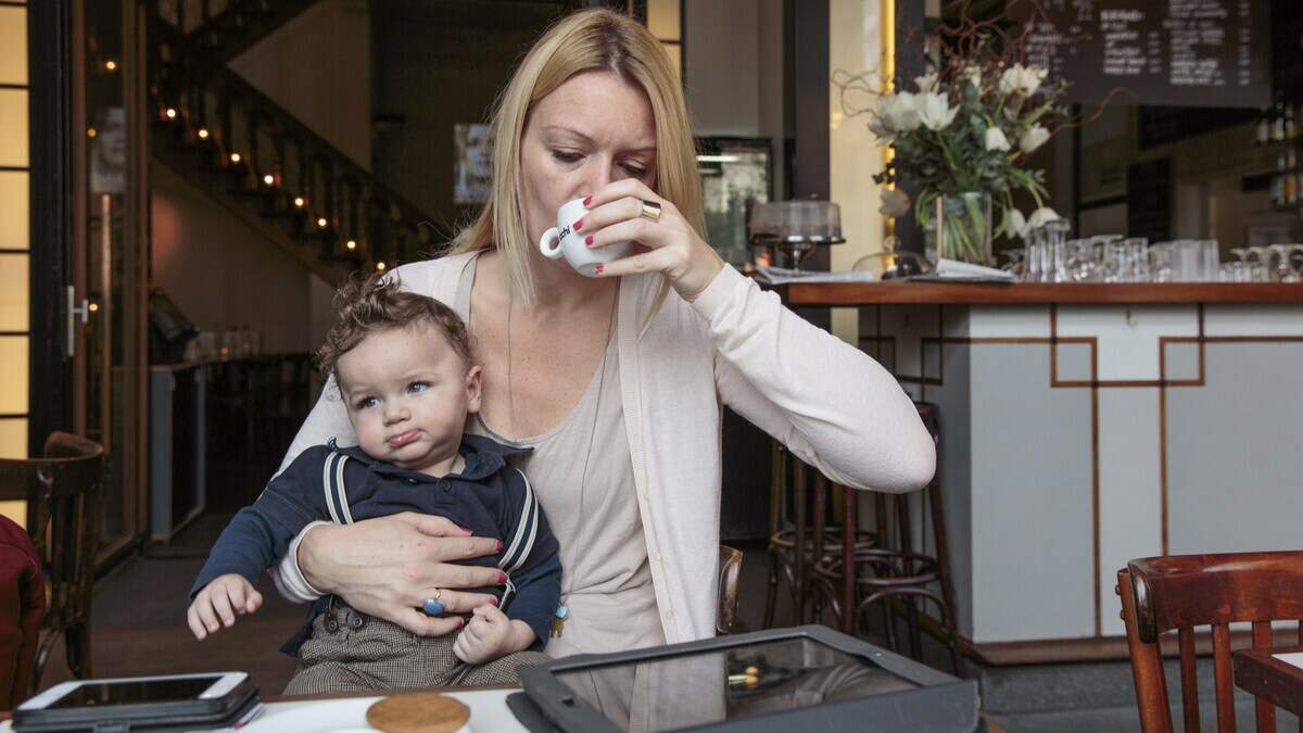 Een werkende vrouw met haar 8 maanden oude zoontje op schoot. Veel vrouwen hebben het gevoel dat ze te veel ballen tegelijk in de lucht moeten houden.