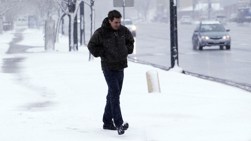 A person braces against the cold on a snowy street.