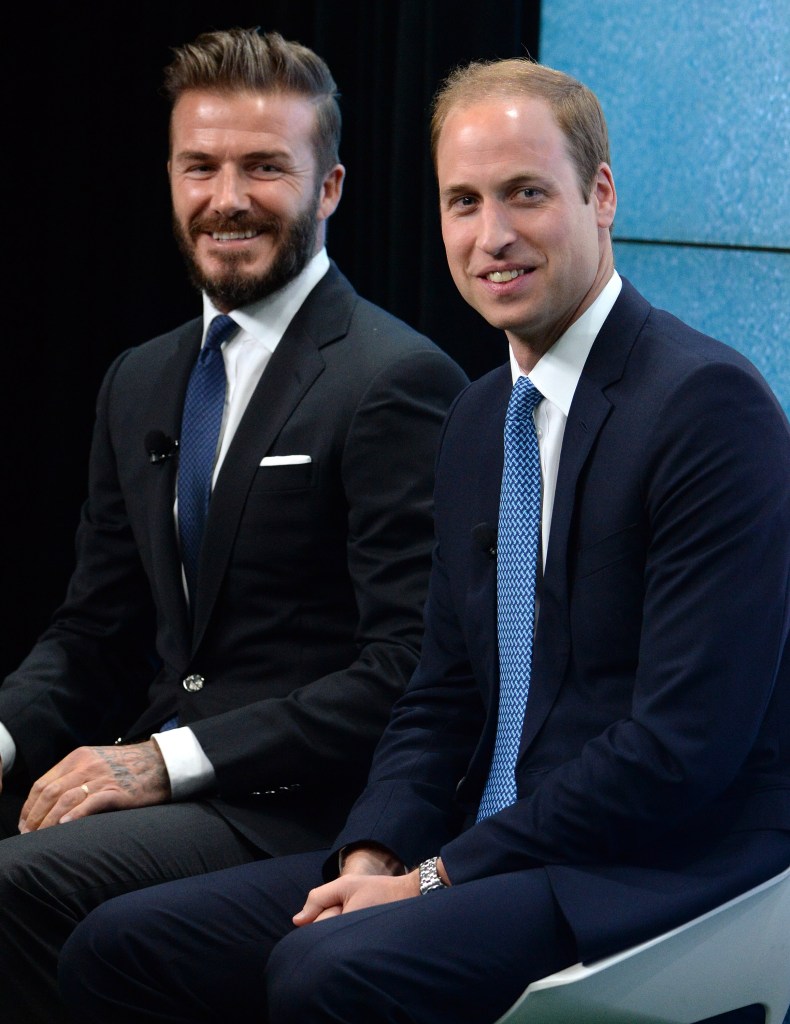 David Beckham and Prince William sitting together smiling at camera