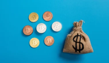 canvas money bag near bitcoins on blue background