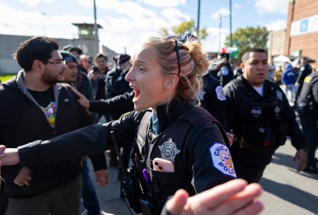 Chicago police officers hold back the crowd as federal immigration officers depart on Oct. 23, 2025, after a raid at the Discount Mall on West 26th Street in Little Village. (Brian Cassella/Chicago Tribune)