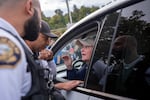 Portland police officers talk with a woman attempting to drive through the protesters outside the U.S. Immigration and Customs Enforcement facility in Portland, Ore., on Sept. 28, 2025. 
