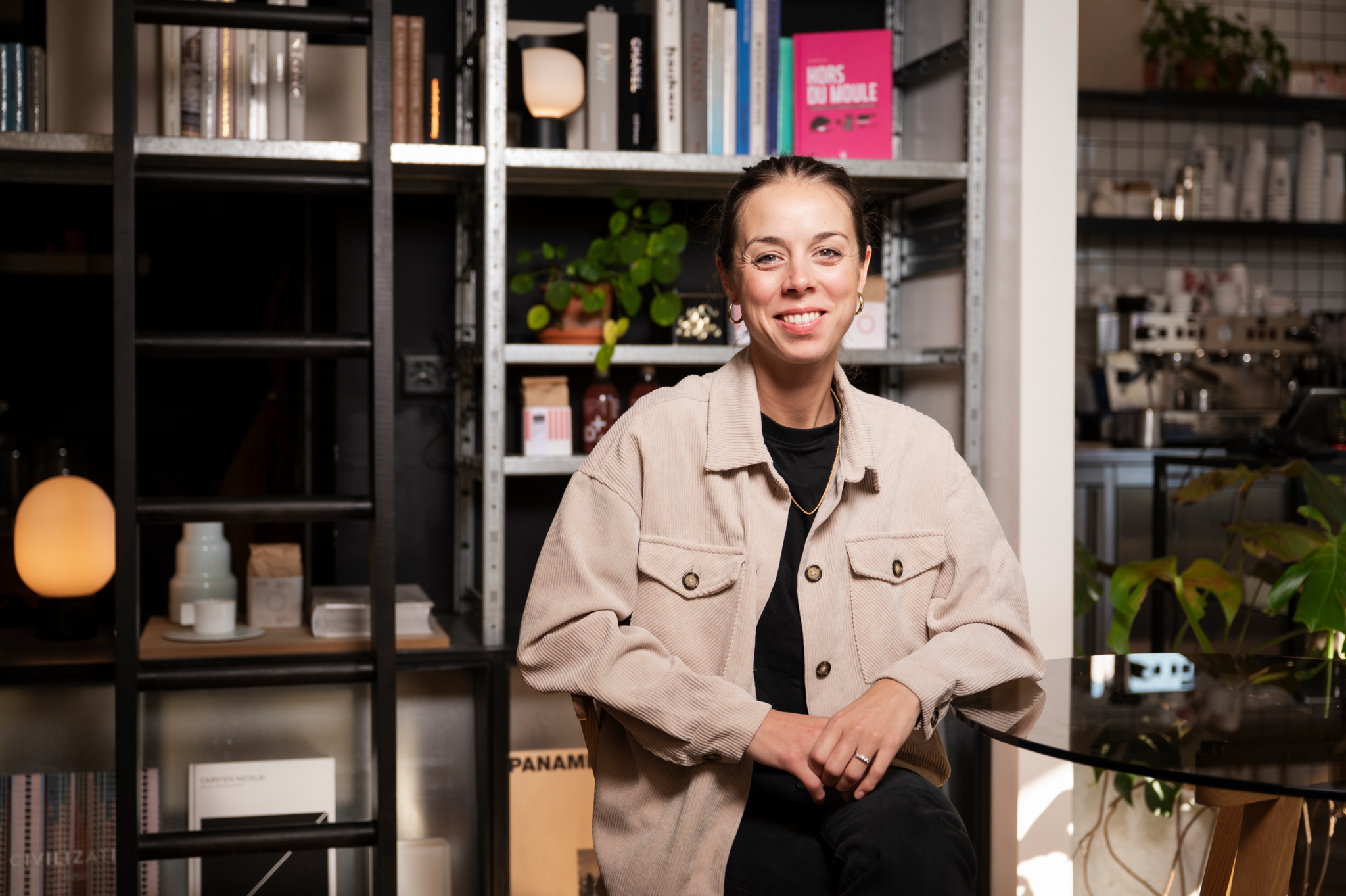 Alba Farnos Viñals, cheffe catalane, assise à Coffee Page à Lausanne, souriant, entourée de livres et plantes, 7 octobre 2025. Alba Farnos Viñals, cheffe catalane, assise à Coffee Page à Lausanne, souriant, entourée de livres et plantes, 7 octobre 2025.