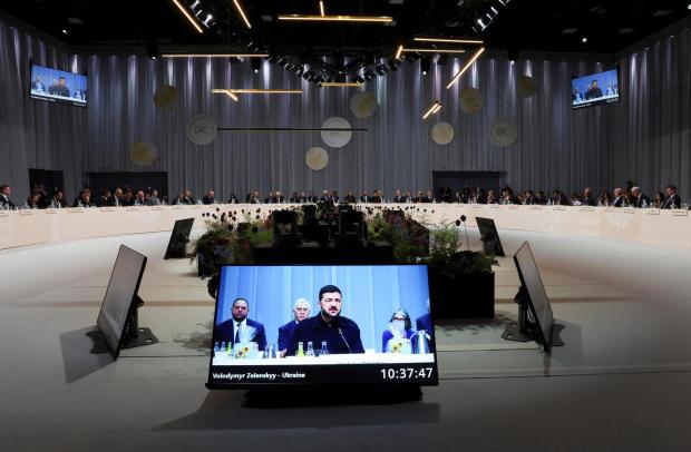Ukrainian President Volodymyr Zelenskyy is seen on a giant screen...