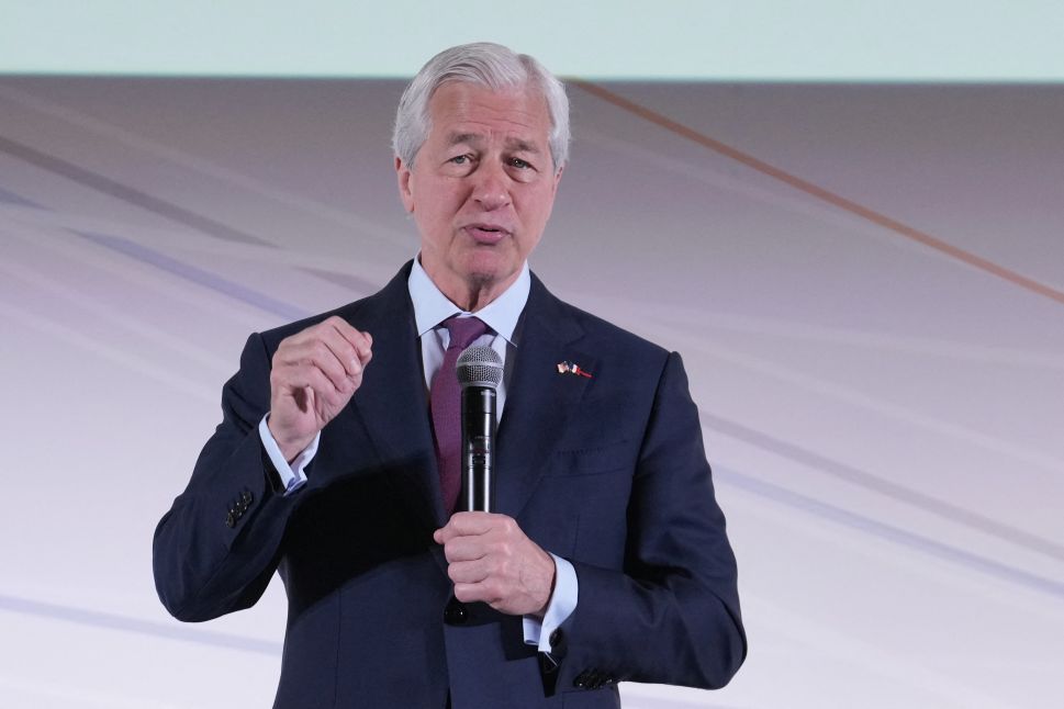 Man in suit stands onstage and speaks into microphone
