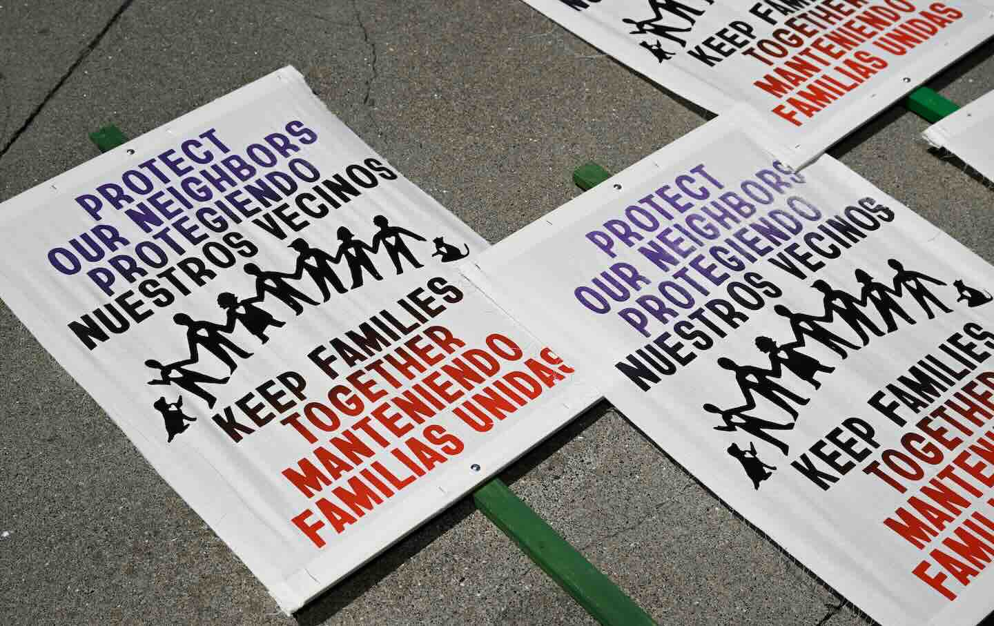 Protest signs on the ground outside of the Phillip Burton Federal Building in San Francisco in July that read, “Protect Our Neighbors / Protegiendo Nuestros Vecinos” and“ Keep Families Together / Manteniendo Familias Unidas.”