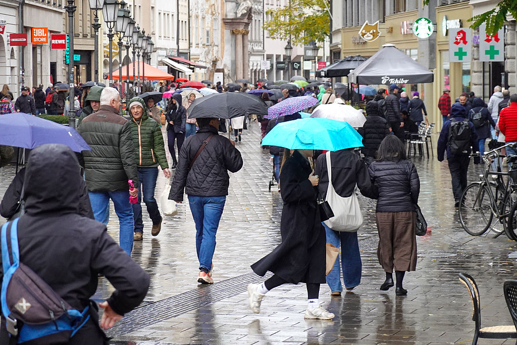 Shoppers With Umbrellas Walk Through Munich Pedestrian Zone On A Rainy Day