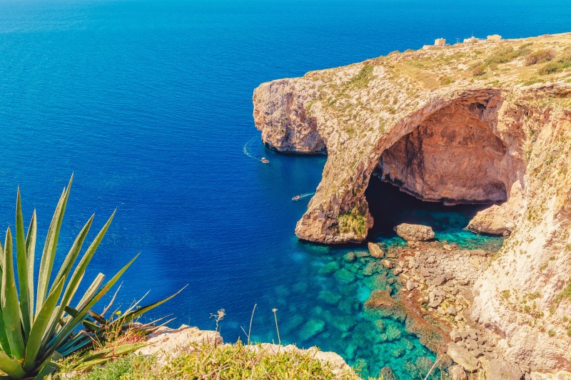Blue Grotto in Malta. Pleasure boat with tourists runs. Natural arch window