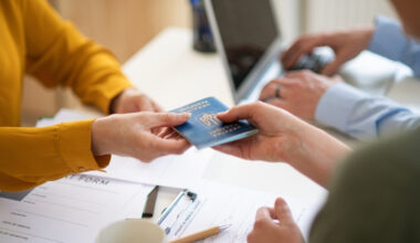 Two hands handing over a passport.