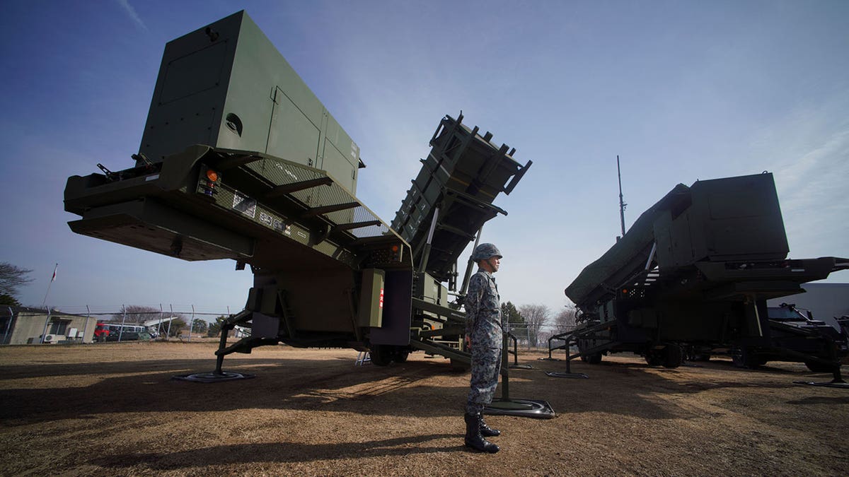 A member of the Japan Ground Self-Defense Force stands guard next to a surface-to-air Patriot Advanced Capability-3 (PAC-3) missile interceptor