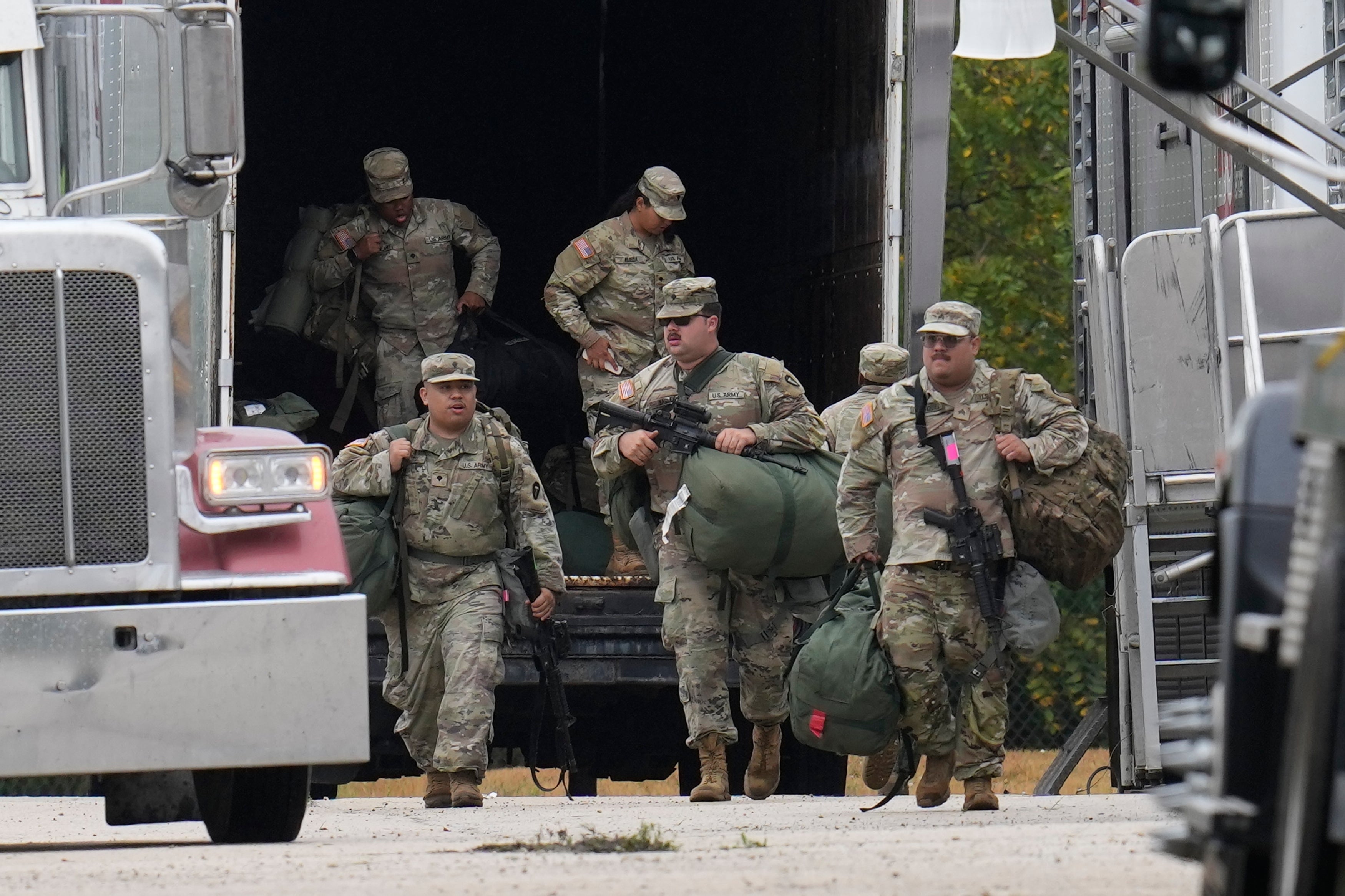 Texas National Guard members unload from a truck at the U.S. Army Reserve Center in Elwood, Illinois, on Oct. 7, 2025