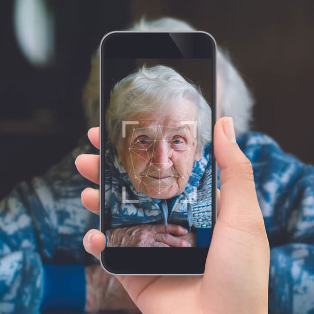 a person holding a phone up in front of an elderly person, whose face is visible on the screen